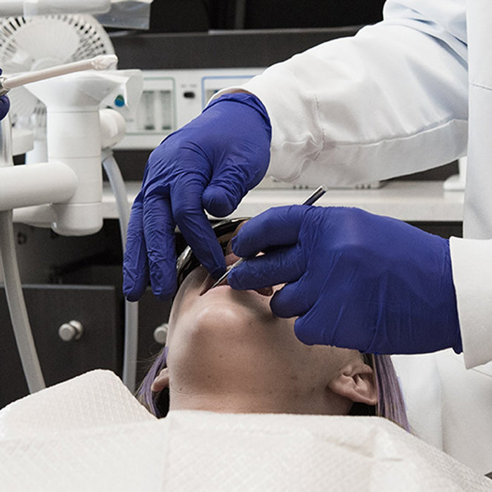 Dental Technician in Indigo Nitrile Gloves Examining Patient Mouth 