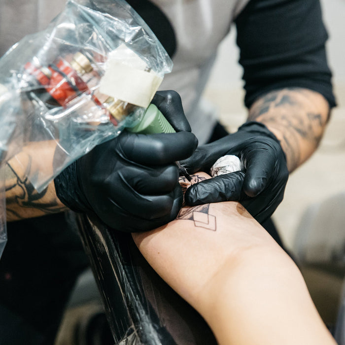 Tattoo Artist in Black Nitrile Gloves Tattooing Hand of Client