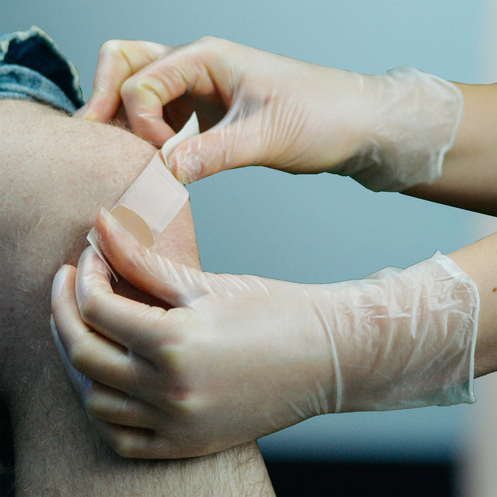 Vinyl Gloved Hands Applying Bandage to a Knee